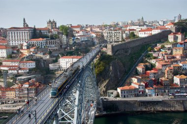Porto, Portekiz; Mart, 28,2022; Dom Luis Demir Köprüsü günbatımında metro ve Porto evleri içinden geçerken