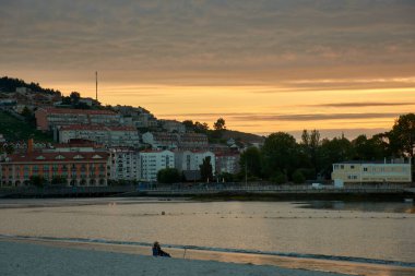Sabaris 'teki Ladeira Sahili' nde gün batımının huzurlu güzelliği. Yumuşak bulutlar ufuk çizgisini geçiyor, sahneye zarafet katıyor. Sakin sular canlı renkleri yansıtıyor, büyüleyici bir manzara yaratıyor..