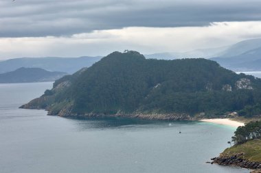 İspanya, Galiçya açıklarındaki Cies Adaları 'nın etkileyici güzelliğinin resmi. Görüntü, Atlantik Okyanusu 'nun turkuaz sularının yavaşça kayalık sahili kapladığı muhteşem bir uçurumu gösteriyor.