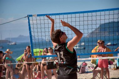 Baiona 'da düzenlenen 3x3 Ladeira Plaj Voleybol Turnuvası' nda oyuncular kollarını kaldırıp ağda güçlü bir blok oluşturdular. Sahne, plaj voleybolunda gerekli rekabet ruhunu ve takım çalışmasını yakalıyor..