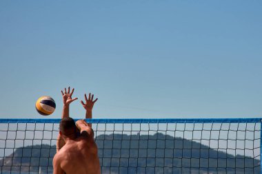 Baiona 'da düzenlenen 3x3 Ladeira Plaj Voleybol Turnuvası' nda oyuncular kollarını kaldırıp ağda güçlü bir blok oluşturdular. Sahne, plaj voleybolunda gerekli rekabet ruhunu ve takım çalışmasını yakalıyor..