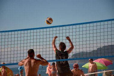 Baiona 'da düzenlenen 3x3 Ladeira Plaj Voleybol Turnuvası' nda oyuncular kollarını kaldırıp ağda güçlü bir blok oluşturdular. Sahne, plaj voleybolunda gerekli rekabet ruhunu ve takım çalışmasını yakalıyor..