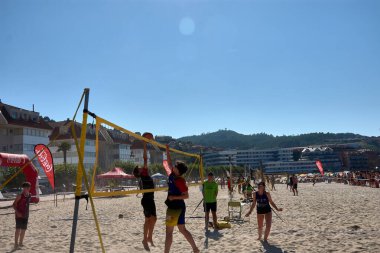 Sabaris, Baiona, Pontevedra, İspanya; 08,27,2024; Baiona 'da düzenlenen 3x3 Ladeira Plaj Voleybol Turnuvası sırasında, oyuncular bir hücum ve bir blok ile yoğun bir net mücadeleye giriştiler. Bu yüksek enerjili an atletizmi ve stratejiyi yakalıyor., 
