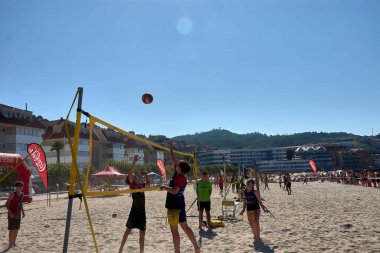 Sabaris, Baiona, Pontevedra, İspanya; 08,27,2024; Baiona 'da düzenlenen 3x3 Ladeira Plaj Voleybol Turnuvası sırasında, oyuncular bir hücum ve bir blok ile yoğun bir net mücadeleye giriştiler. Bu yüksek enerjili an atletizmi ve stratejiyi yakalıyor., 