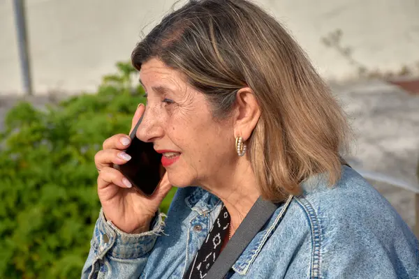 stock image Older Woman Communicating on Mobile Phone, Looking Concerned. Her focused look suggests an important or concerning conversation.