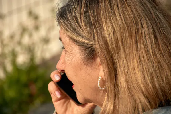 stock image Older Woman Communicating on Mobile Phone, Looking Concerned. Her focused look suggests an important or concerning conversation.