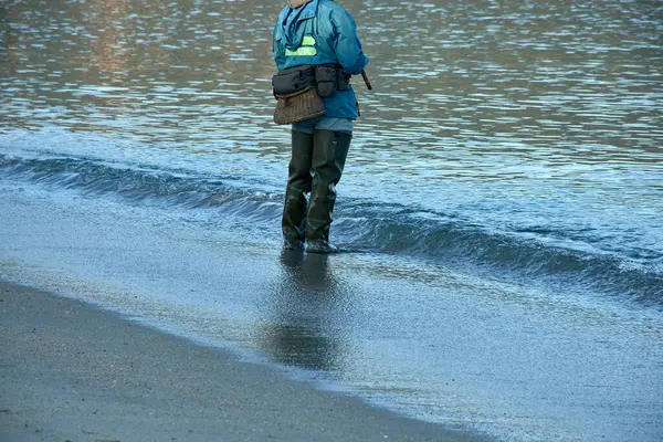 stock image the traditional attire of a fisherman wading in the water, equipped with sturdy boots and a basket for holding the catch. 