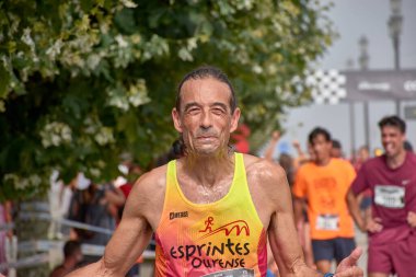 Bayona,Pontevedra,Spain August,18,2024; the determination of participants is evident as they cross the finish line, utterly exhausted but victorious. This image captures the raw emotion and physical toll of the race, with runners gasping for breath,  clipart