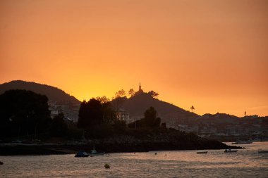 Bayona 'daki Ladeira Sahili' nde olağanüstü bir gün batımı. Canlı turuncu renkler gökyüzünü boyuyor. Büyüleyici ve unutulmaz bir manzara yaratıyor. Güneş ufkun altına batıyor, sakin sular ve kumlu kıyılar boyunca ılık ve ışıl ışıl parlıyor.. 