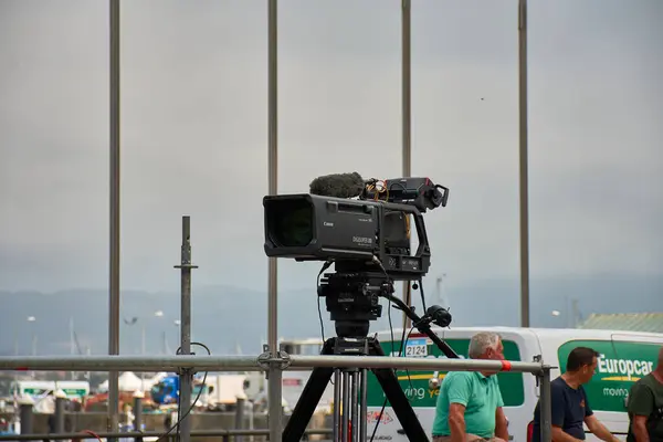 stock image Bayona,Pontevedra,Spain; August,27,2024; A television camera poised and ready to begin broadcasting. The camera, equipped with a large lens and mounted on a professional tripod, is positioned at the perfect angle, ready to capture the unfolding actio