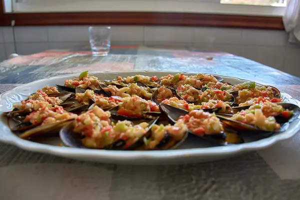 stock image Close-up of a plate of freshly prepared mussels topped with a vibrant vinaigrette dressing. The dish is beautifully presented with chopped vegetables such as onions and red and green peppers, which add a burst of color and flavor. 