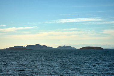 İspanya, Pontevedra, Bayona 'daki Montereal' den Cies ve Estelas Adaları manzarası. Görüntü adaların engebeli siluetlerini ön planda Atlantik Okyanusu 'nun derin maviliğiyle yumuşak, altın bir gökyüzüne karşı sergiliyor.