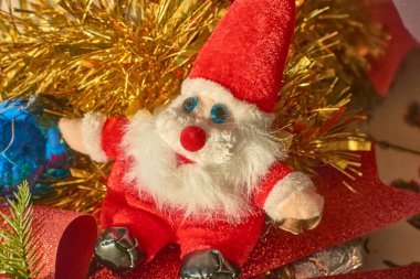 Parlak kırmızı bir yay, çam kozalakları ve kırmızı böğürtlen ile çevrili parlak mavi bir mücevher içeren renkli ve şenlikli bir Noel süsü.. 