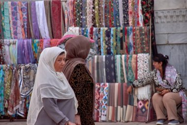 Taşkent, Özbekistan; Eylül, 16. 2024: Özbekistan 'ın başkenti Taşkent' te hareketli bir pazarda yürürken çarpıcı sarı başörtüsü takan Müslüman bir kadın. 
