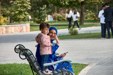 Taşkent, Özbekistan; Eylül, 16. 2024: Özbekistan 'ın başkenti Taşkent' te hareketli bir pazarda yürürken çarpıcı sarı başörtüsü takan Müslüman bir kadın. 