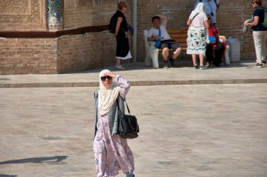 Taşkent, Özbekistan; Eylül, 16. 2024: Özbekistan 'ın başkenti Taşkent' te hareketli bir pazarda yürürken çarpıcı sarı başörtüsü takan Müslüman bir kadın. 