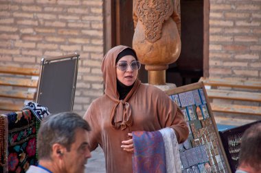 Taşkent, Özbekistan; Eylül, 16. 2024: Özbekistan 'ın başkenti Taşkent' te hareketli bir pazarda yürürken çarpıcı sarı başörtüsü takan Müslüman bir kadın. 
