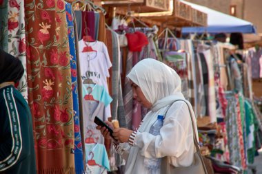 Taşkent, Özbekistan; Eylül, 16. 2024: Özbekistan 'ın başkenti Taşkent' te hareketli bir pazarda yürürken çarpıcı sarı başörtüsü takan Müslüman bir kadın. 