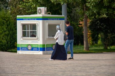 Taşkent, Özbekistan; Eylül, 16. 2024: Beyazlar içinde, eşiyle birlikte Özbekistan 'ın hareketli caddelerinde yürüyen genç bir Müslüman kadın. Çevrede