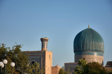 Stunning blue dome and towering minaret of the Gur-e-Amir Mausoleum, the burial site of the conqueror Timur (Tamerlane), located in Samarkand, Uzbekistan. The domes intricate tilework and geometric patterns reflect the Timurid architectural style clipart