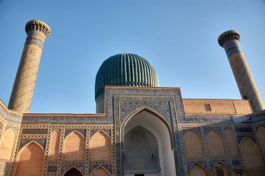 Stunning blue dome and towering minaret of the Gur-e-Amir Mausoleum, the burial site of the conqueror Timur (Tamerlane), located in Samarkand, Uzbekistan. The domes intricate tilework and geometric patterns reflect the Timurid architectural style clipart