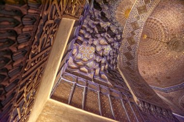 Registan Meydanı, Semerkant, Özbekistan 'daki büyük medreselerden birinin aydınlatılmış iç mekanı. Duvarların ve kemerlerin üzerindeki karmaşık döşemeler ve detaylı İslami desenler akşam ışıklarının altında parlayarak büyüleyici bir atmosfer yaratıyor..