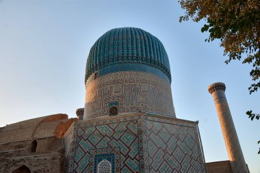 Stunning blue dome and towering minaret of the Gur-e-Amir Mausoleum, the burial site of the conqueror Timur (Tamerlane), located in Samarkand, Uzbekistan.The domes intricate tilework and geometric patterns reflect the Timurid architectural style, clipart