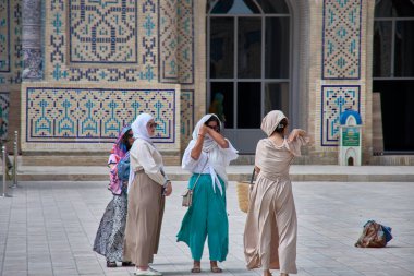 Buhara, Özbekistan; Eylül 19.2024: her biri tesettürlü bir grup Müslüman kadın, Özbekistan 'ın Buhara kentinin tarihi sokaklarında yürüyorlar.. 