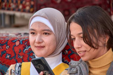 Khiva, Özbekistan; 21 Eylül 2024: Özbekistan 'ın Khiva kentinin pitoresk sokaklarında gezinen iki genç Özbek kadın. 