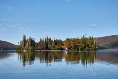 Hırvatistan 'ın Krka Ulusal Parkı' nın merkezinde yer alan Visovac Adası. Ada, yemyeşil ve sakin, yansıtıcı sularla çevrili tarihi Visovac Manastırı 'na ev sahipliği yapıyor. Tepeler ve ormanlardan oluşan bir zemin üzerine kurulmuş Visovac, huzurlu bir ortam sunuyor.