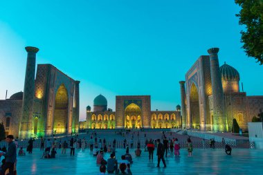 SAMARKAND, UZBEKISTAN - 17 Eylül 2024: Semerkant, Özbekistan 'daki Registan Meydanı, akşam gökyüzünün altında aydınlandı. Tarihi İpek Yolu boyunca önemli bir konum olarak Registan Meydanı üç büyük medresesi ile ünlüdür., 