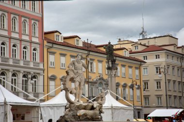 Piazza della Borsa, Trieste, İtalya 'daki Neptün ve İmparator I. Leopold heykelleri. Neptün heykeli şehrin derin deniz bağlantılarını sembolize ederken, I. Leopold heykeli Avusturya-Macaristan tarihini yansıtıyor.. 