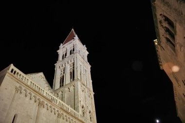 Hırvatistan 'ın Trogir kentindeki Saint Lawrence Katedrali gece gökyüzüne karşı güzelce aydınlatıldı. Bu Roma katedralinin mimari ihtişamı, karmaşık ayrıntıları ve yüksek çan kulesiyle dramatik bir şekilde göze çarpıyor.