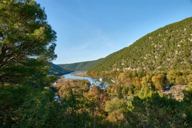 Hırvatistan 'ın çarpıcı Krka Ulusal Parkı' ndan geçen bir turist botu, Skradin kasabasından ünlü Skradinski Buk şelalelerine seyahat ediyor. Manzaralı tekne yolculuğu yolculara parkların doğal güzelliği hakkında ilginç bir deneyim sunuyor.