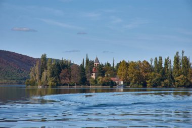 Hırvatistan 'ın Krka Ulusal Parkı' nın merkezinde yer alan Visovac Adası. Ada, yemyeşil ve sakin, yansıtıcı sularla çevrili tarihi Visovac Manastırı 'na ev sahipliği yapıyor. Tepelerin ve ormanların olduğu bir zemin üzerine kurulmuş