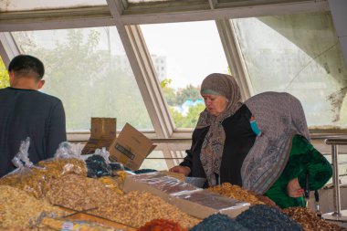 TASHKENT, UZBEKISTAN - 16 DE SEPTIEMBRE DE 2024: Taşkent, Özbekistan 'daki ünlü Chorsu Çarşısını ziyaret eden Arap kadınları. Geleneksel giysiler içinde, bu kadınlar yerel ürünler, baharatlar ve ürünlerle dolu, hareketli pazarı keşfediyorlar.. 