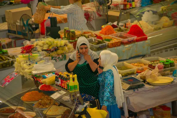 TASHKENT, UZBEKISTAN - 16 DE SEPTIEMBRE DE 2024: Taşkent, Özbekistan 'daki ünlü Chorsu Çarşısını ziyaret eden Arap kadınları. Geleneksel giysiler içinde, bu kadınlar yerel ürünler, baharatlar ve ürünlerle dolu, hareketli pazarı keşfediyorlar.. 