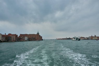 Venedik, İtalya; Ekim, 17. 2024: Stucky Mill, İtalya 'nın Venedik kentindeki Giudecca adasında lüks bir otele dönüşen eski bir sanayi binası. Tarihi yapının kırmızı tuğlalı peradı etrafındaki suya karşı duruyor.