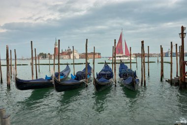 Venedik, İtalya; Ekim, 17. 2024: sakin suların şehrin tarihi ufuk çizgisini yansıttığı Venedik 'in sakinliği. Yanaşmış gondollar, Venedik cazibesinin özünü somutlaştıran sakin kanalda yavaşça sallanıyor..