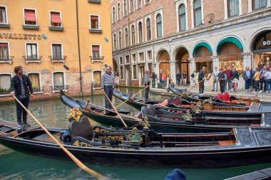 Venedik, İtalya; Ekim, 17. 2024: Venedik 'te güneşli bir günde gondolcular, yüzyıllardır el üstünde tutulan bir geleneği sergileyerek şehrin pitoresk kanallarında ustaca gezinirler..