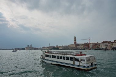 Venedik, İtalya; Ekim, 17. 2024: Venedik 'te günlük hayat, kanallarda gezinen buharlıların yoğun trafiğini gösteriyor. Arka planda, şehrin çarpıcı mimarisi ufuk çizgisine karşı yükselir ve canlı bir şehir manzarası yaratır..