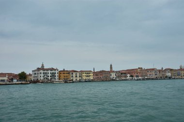 Venedik, İtalya; Ekim, 17. 2024: bulutlu bir günde Venedik kanalının melankolik güzelliği. Bulutlu gökyüzünden gelen yumuşak gölgeler sakin sulara ve kanalı çevreleyen tarihi binalara yavaşça düşerek sakin ve sakin bir atmosfer yaratıyor.