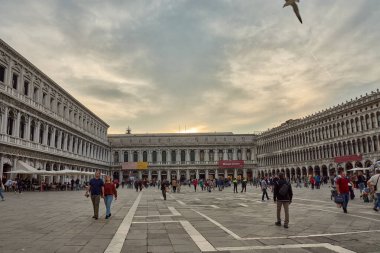 Venice,Italy;October,17,2024:St. Mark's Square, the vibrant heart of Venice, buzzes with life as visitors indulge in outdoor coffee amidst its stunning surroundings. clipart