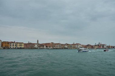 Venedik, İtalya; Ekim, 17. 2024: bulutlu bir günde Venedik kanalının melankolik güzelliği. Bulutlu gökyüzünden gelen yumuşak gölgeler sakin sulara ve kanalı çevreleyen tarihi binalara yavaşça düşerek sakin ve sakin bir atmosfer yaratıyor.