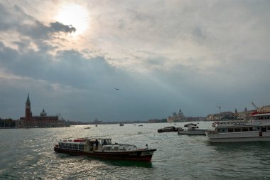 Venice,Italy;October,17,2024:everyday life in Venice, showcasing the busy traffic of vaporettos navigating the canals. In the background, the stunning architecture of the city rises against the skyline, creating a vibrant urban scene. clipart