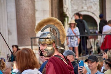 Hırvatistan 'ın Split kenti; 12 Ekim 2024: Turistler Hırvatistan' ın Split kentindeki Diocletian Sarayı 'nda Romalı askerler gibi giyinmiş sanatçılarla neşe içinde fotoğraf çekiyorlar. Bu UNESCO Dünya Mirası sahasının antik arkaplanı bu sahneye eşsiz bir cazibe katıyor