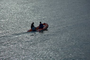 Nigran, Pontevedra, İspanya; Aralık 03.2024: Sakin sularda yol alan, şişme motorlu bir teknede iki denizcinin hava görüntüsü. Görüntü teknelerin hareketini yakalıyor ve denizciler yolculuklarına odaklanıyor.. 