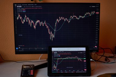 Vigo, Pontevedra, İspanya; 19 Aralık 2024: Bu resim üç dijital cihazlı modern bir kripto para birimi kurulumunu gösteriyor: bir bilgisayar monitörü, bir tablet ve bir akıllı telefon.. 