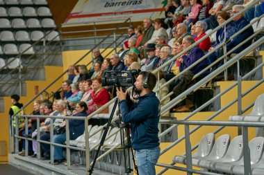 Vigo, İspanya 11 Ocak 2025: Bu görüntüde profesyonel kamera kurulumu ile önemli bir olayı kaydeden bir televizyon kameramanı yer alıyor. Odaklanmış ve istikrarlı kameraman, gerçek-t 'nin yakalanmasında medya profesyonellerinin temel rolünü gösteriyor.
