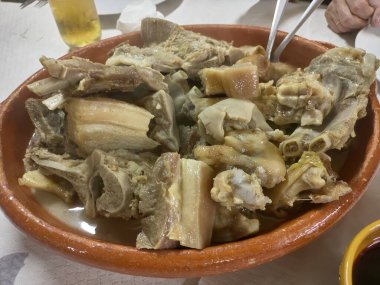 Bu resimde geleneksel bir Galiçya cocido 'su kırsal bir kasede servis ediliyor. İçten gelen yemekte, mevsimlik sebzeler ve lezzetli bir et suyuyla birlikte yavaşça pişirilmiş domuz eti parçaları bulunuyor. Ben...